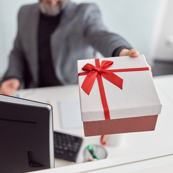 Un gros plan d'un coffret cadeau haut de gamme ouvert contenant un collier avec pendentif en or minimaliste, un bracelet assorti et une bague délicate disposés sur un tissu doux.